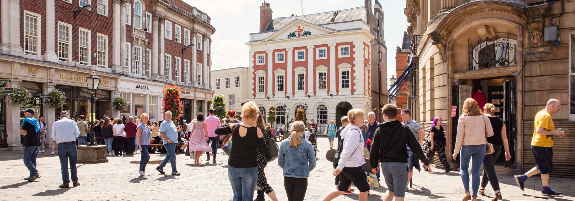 A view of the Mansion House from a distance with crowds of people walking in front of the entrance