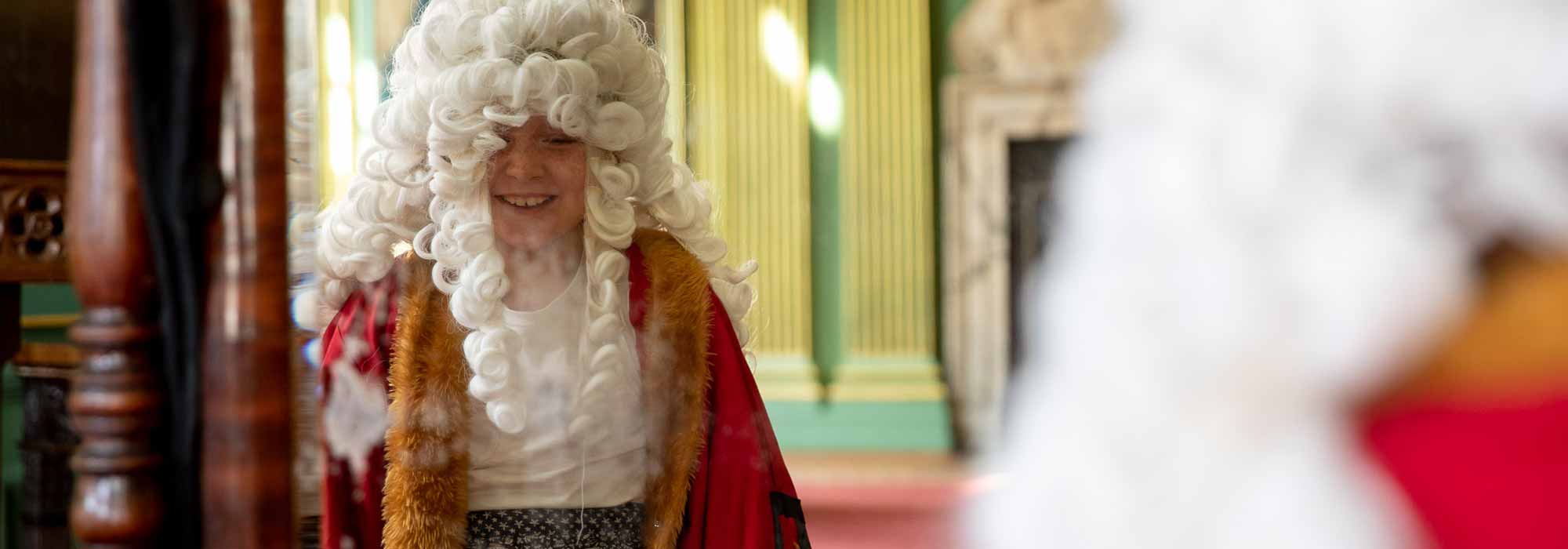 A young child laughs whilst dressing up as the Lord Mayor