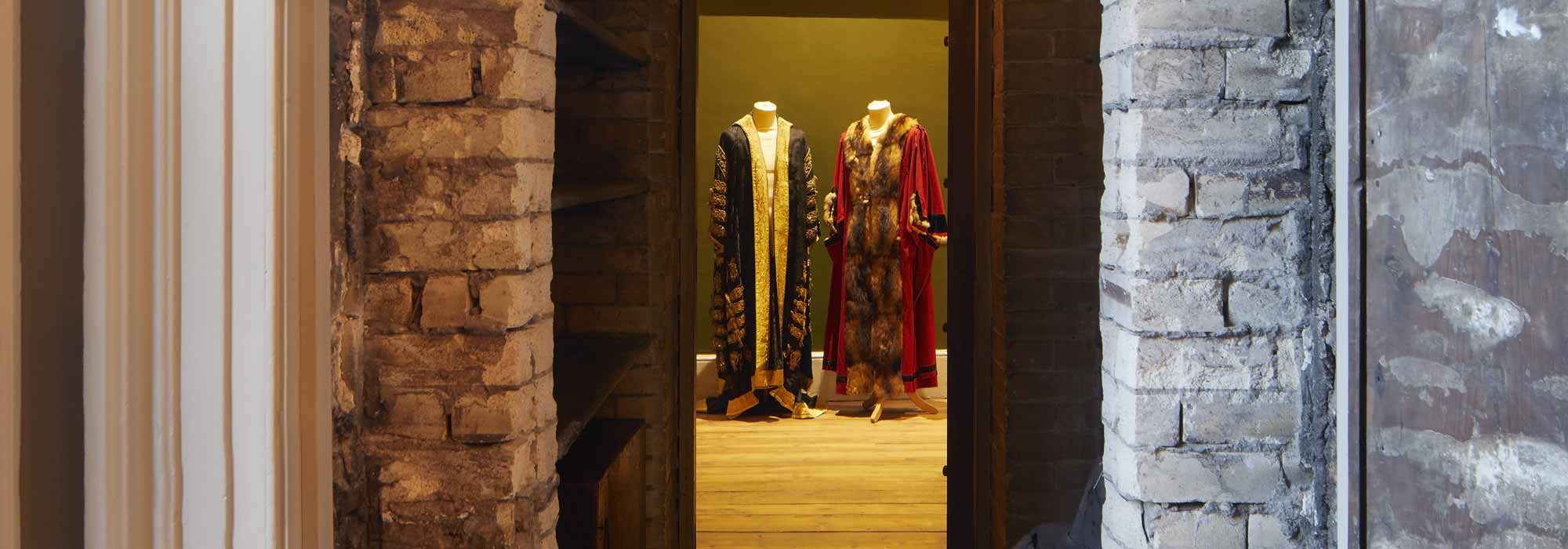 stone doorway through which 2 mannequins display cloaks