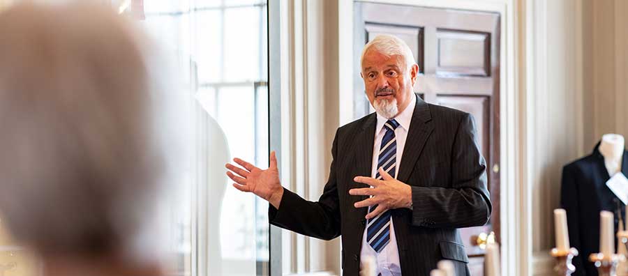 A man in a suit explains something to a group of visitors