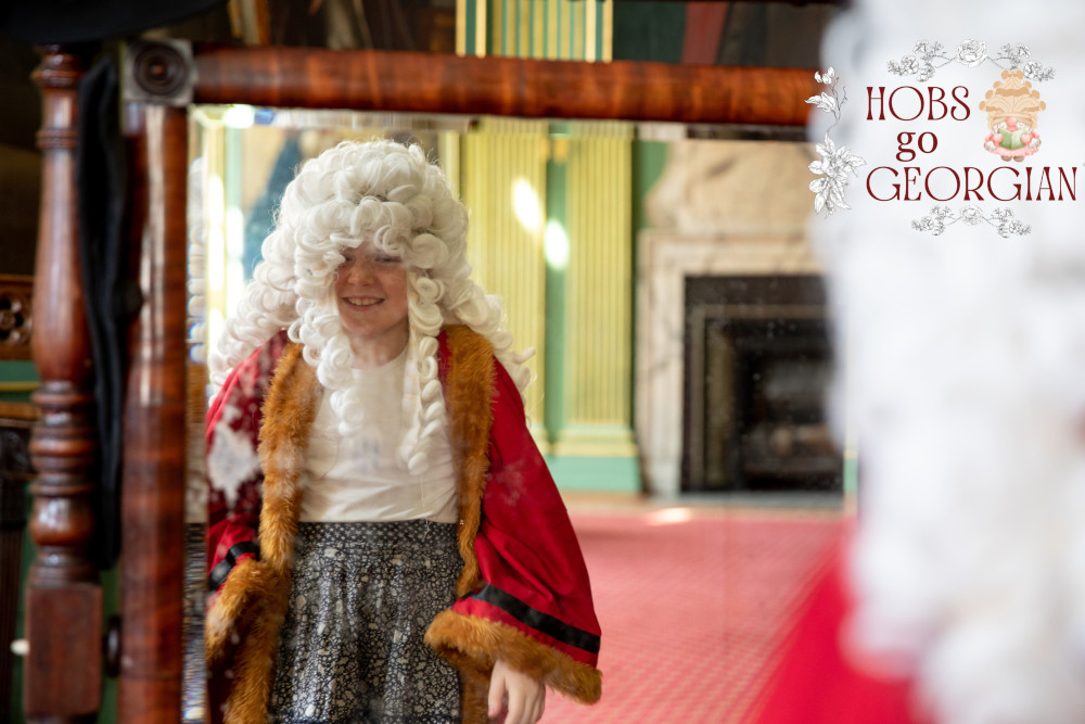 A young child dresses in Georgian fancy dress, the text on the image says Hobs goes Georgian