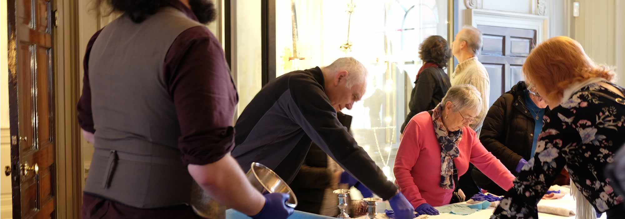 A group of people work around a table wearing purple protective gloves.