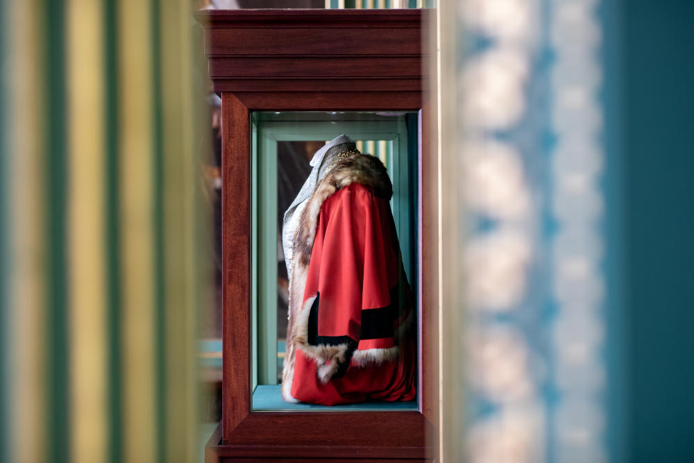 Display cabinet in the Mansion House displaying a red coat which is fur lined