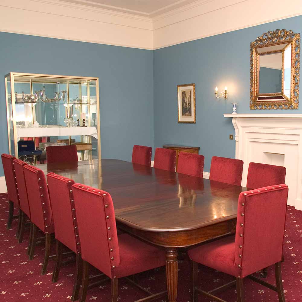 A boardroom table and chairs located in front of a fire place.