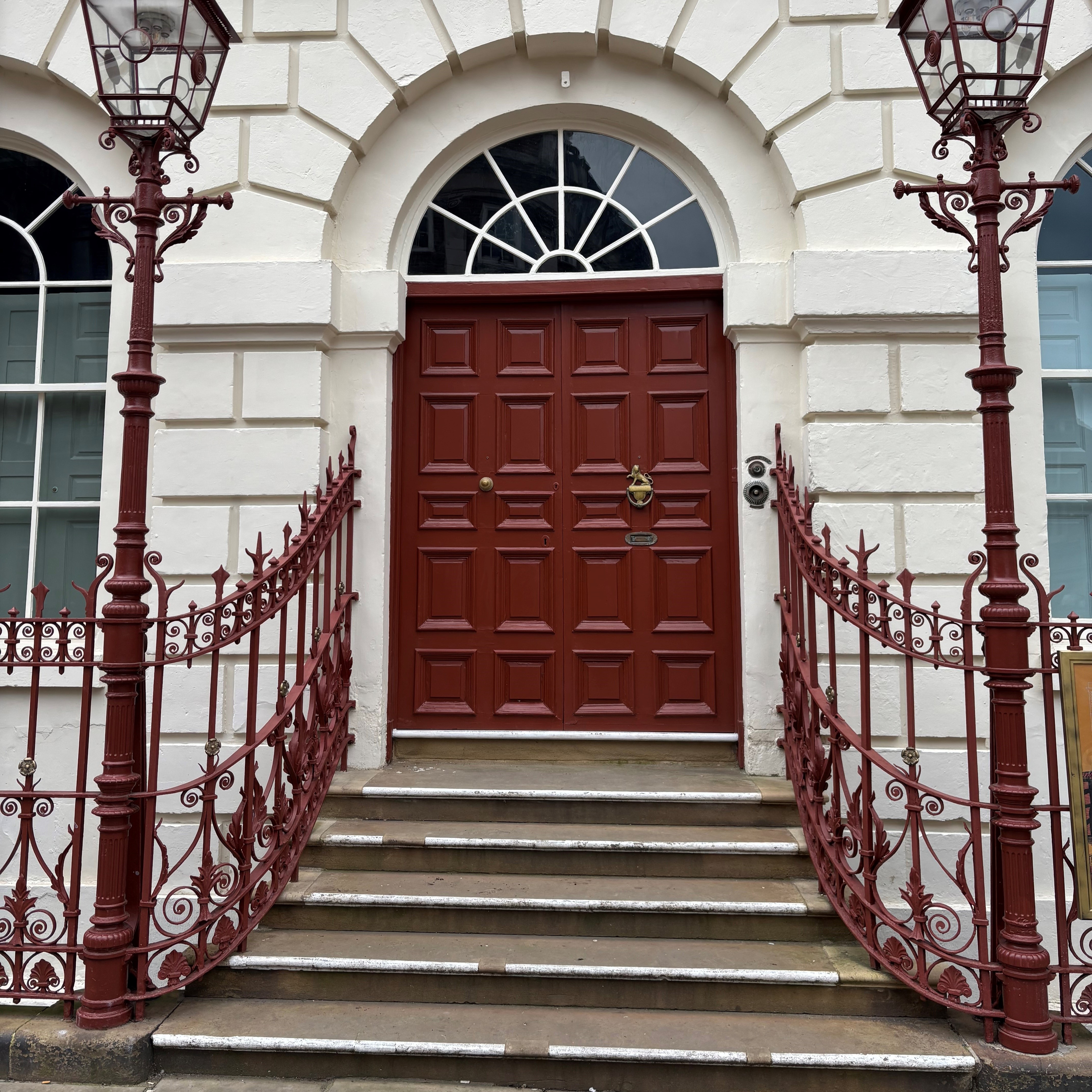 Entrance used for accessing the House, shows the white brick exterior of Mansion House with a red door